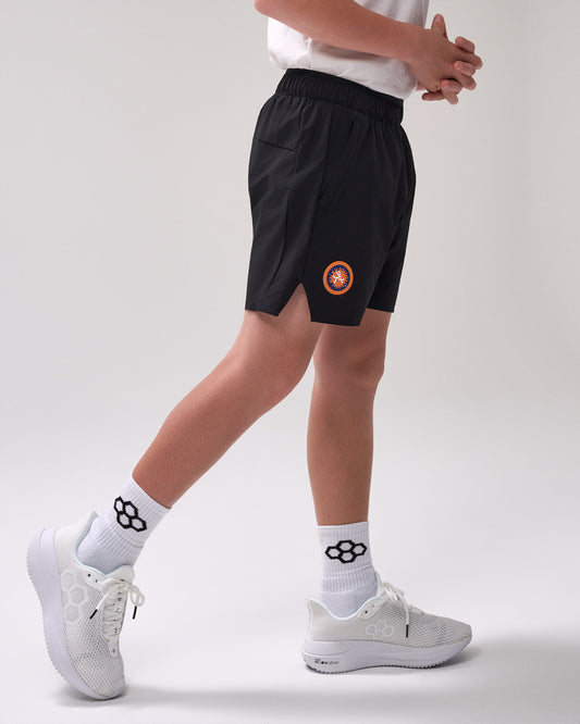 Person wearing black shorts with a 'United World Wrestling' logo, white socks, and white sneakers on a light gray background