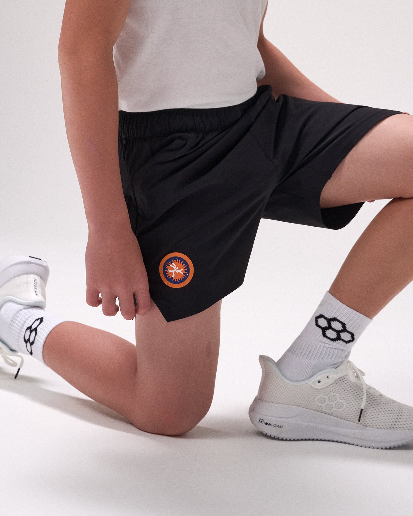 Person wearing black shorts with a 'United World Wrestling' logo, white socks, and white sneakers on a light background