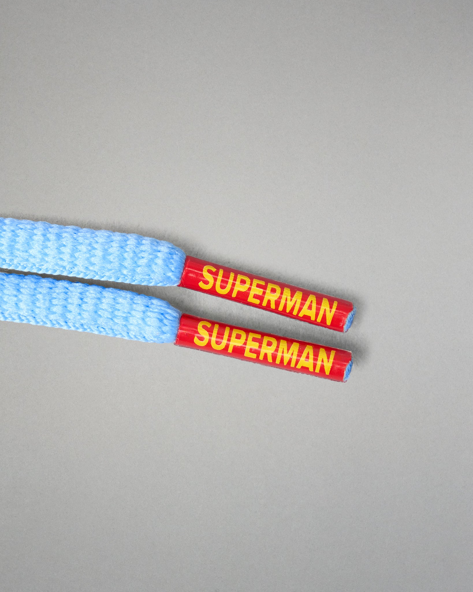 Close-up of light blue RUDIS JB1 Superman wrestling shoe laces with red and yellow Superman branded lace tips.