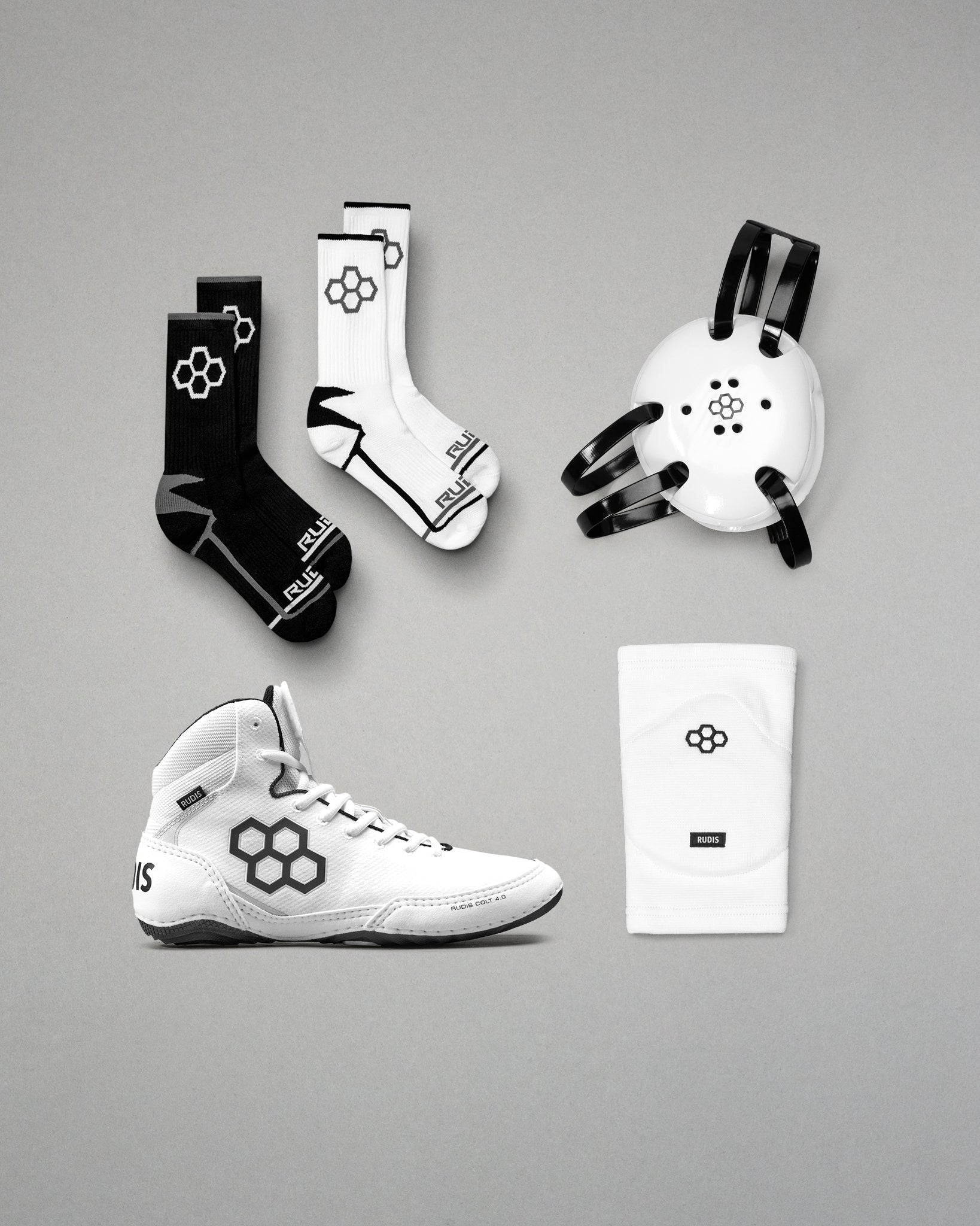Collection of sports gear including wrestling shoes, socks, and headgear on a gray background